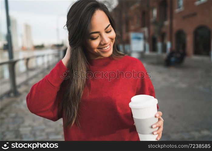 Portrait of beautiful young woman holding a cup of coffee outdoors. Urban concept.