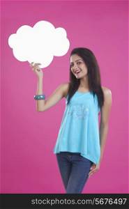 Portrait of beautiful young woman holding thought bubble over pink background