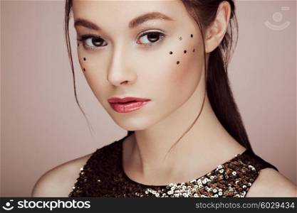 Portrait of beautiful young woman in a shiny golden dress. Brunette girl. Perfect make-up. Freckles