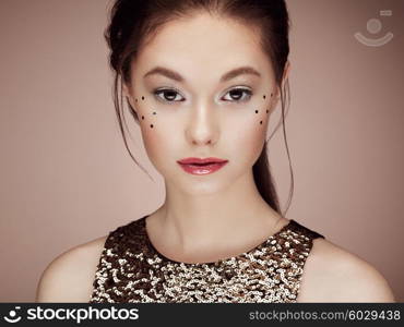 Portrait of beautiful young woman in a shiny golden dress. Brunette girl. Perfect make-up. Freckles