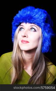 Portrait of beautiful young woman in blue winter hat on black background