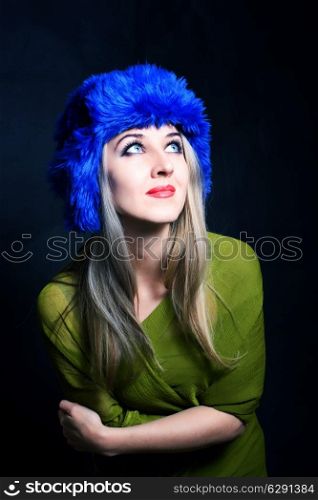 Portrait of beautiful young woman in blue winter hat on black background ???????