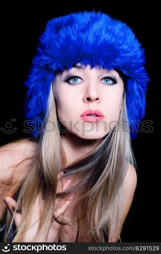 Portrait of beautiful young woman in blue winter hat on black background
