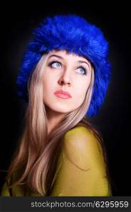 Portrait of beautiful young woman in blue winter hat on black background closeup