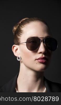Portrait of Beautiful young woman in sunglasses on black background