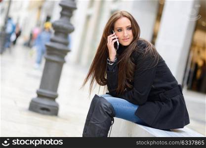 Portrait of beautiful young woman in urban background talking on phone