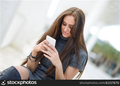 Portrait of beautiful young woman in urban background writting on phone
