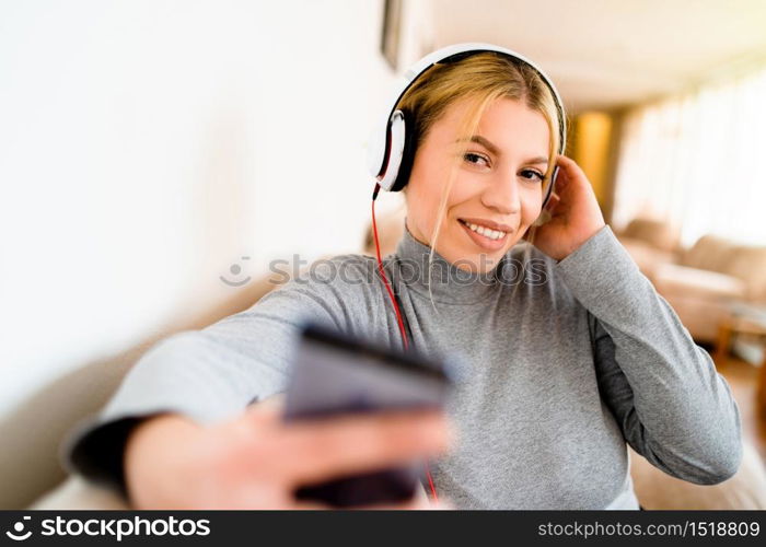 Portrait of beautiful young woman listen to the music via mobile phone headphones at the hotel on the vacation holiday home