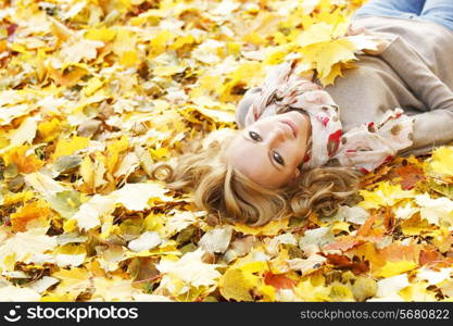 Portrait of beautiful young woman lying outdoors in autumn park