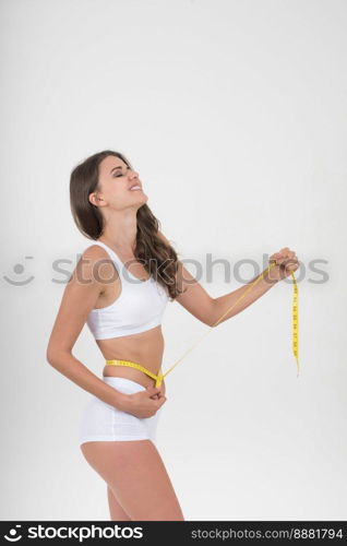 Portrait of beautiful young woman measuring her figure size with tape measure