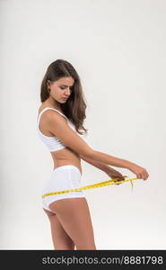 Portrait of beautiful young woman measuring her figure size with tape measure