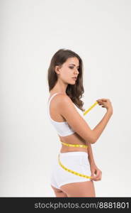 Portrait of beautiful young woman measuring her figure size with tape measure