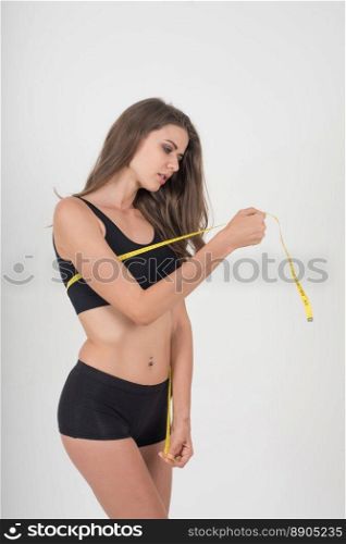 Portrait of beautiful young woman measuring her figure size with tape measure