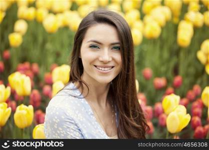 Portrait of beautiful young woman on the background of tulips