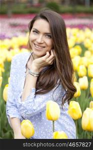 Portrait of beautiful young woman on the background of tulips
