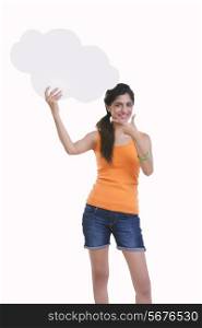 Portrait of beautiful young woman pointing at thought bubble over white background