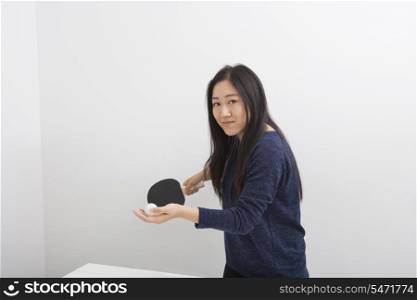 Portrait of beautiful young woman preparing to serve table tennis ball