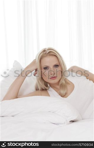 Portrait of beautiful young woman reclining in bed