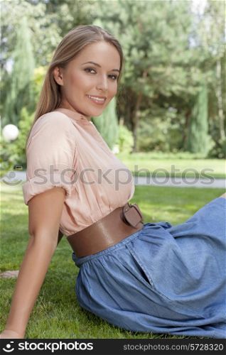 Portrait of beautiful young woman relaxing on grass in park
