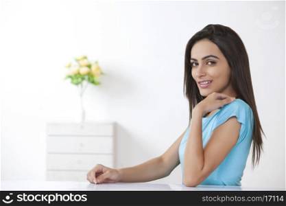 Portrait of beautiful young woman sitting at table in house