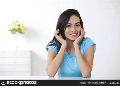 Portrait of beautiful young woman sitting at table in house