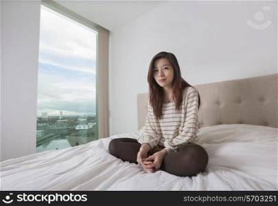 Portrait of beautiful young woman sitting on bed