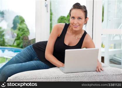 Portrait of beautiful young woman sitting on couch and using laptop