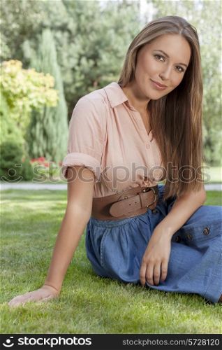 Portrait of beautiful young woman sitting on grass in park