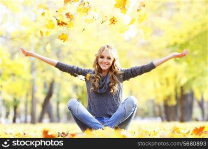Portrait of beautiful young woman sitting outdoors in autumn park