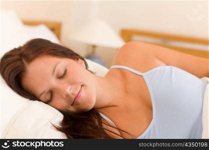 Portrait of beautiful young woman sleeping in white bed