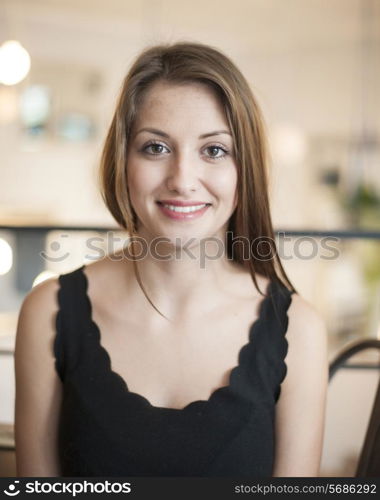 Portrait of beautiful young woman smiling at cafe