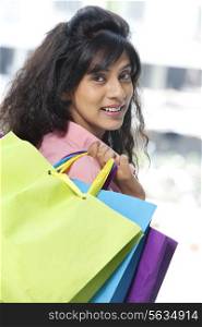 Portrait of beautiful young woman smiling while holding shopping bags