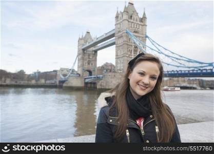Portrait of beautiful young woman standing in front of tower bridge; London; UK