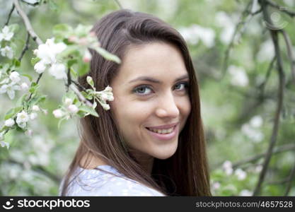 Portrait of Beautiful young woman standing near blooming trees in spring garden