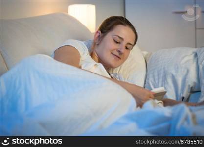 Portrait of beautiful young woman using digital tablet in bed at night