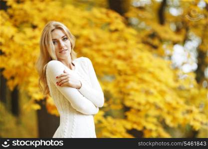 Portrait of beautiful young woman walking outdoors in autumn park