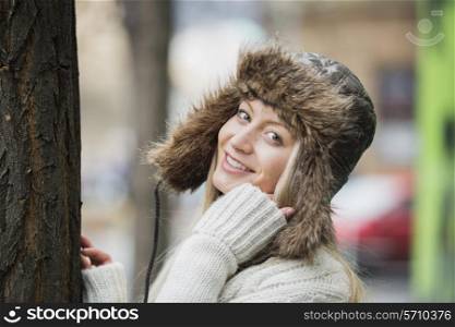Portrait of beautiful young woman wearing fur hat outdoors