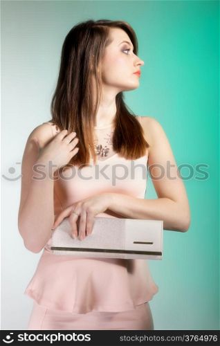 Portrait of beautiful young woman with a handbag. Fashion photo. Green background.