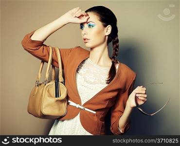 Portrait of beautiful young woman with a leather bag. Fashion photo