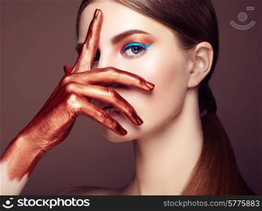 Portrait of beautiful young woman with art make-up. Bronze hand. Beauty fashion