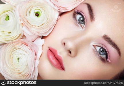 Portrait of beautiful young woman with flowers. Brunette woman with luxury makeup. Perfect skin. Eyelashes. Cosmetic eyeshadow