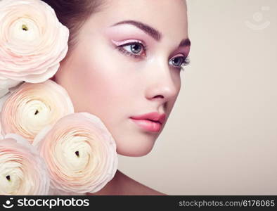 Portrait of beautiful young woman with flowers. Brunette woman with luxury makeup. Perfect skin. Eyelashes. Cosmetic eyeshadow