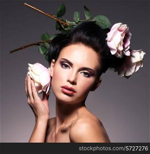 Portrait of beautiful young woman with flowers in hair poses at studio