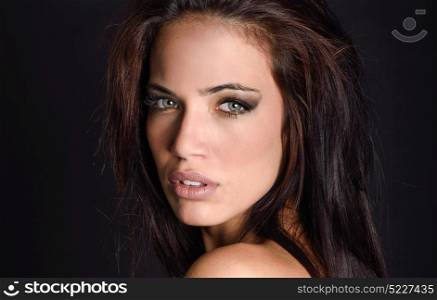 Portrait of beautiful young woman with green eyes on black background