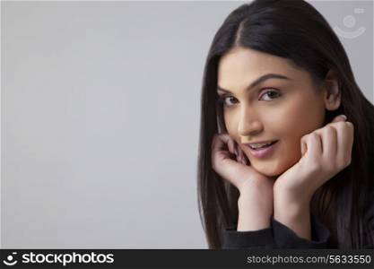 Portrait of beautiful young woman with hand on chin isolated over colored background