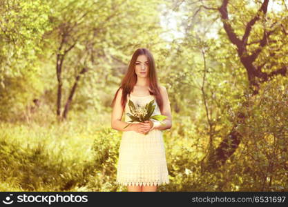 Portrait of beautiful young woman with lily of the valley. Portrait of beautiful young woman with lily of the valley. Girl on nature. Spring flowers. Fashion beauty