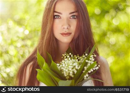 Portrait of beautiful young woman with lily of the valley. Portrait of beautiful young woman with lily of the valley. Girl on nature. Spring flowers. Fashion beauty