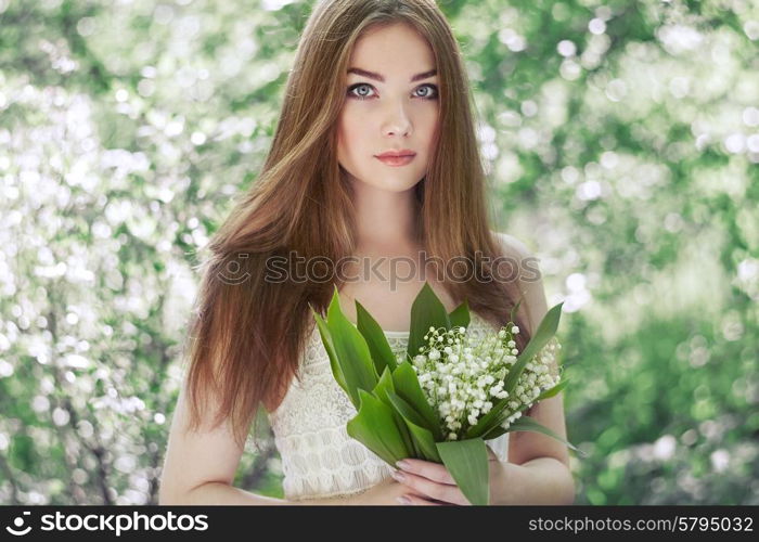 Portrait of beautiful young woman with lily of the valley. Girl on nature. Spring flowers. Fashion beauty