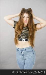 Portrait of beautiful young woman with long brown hair wearing stylish camo pattern tshirt and jeans making funny face.. Beautiful young woman with brown hair