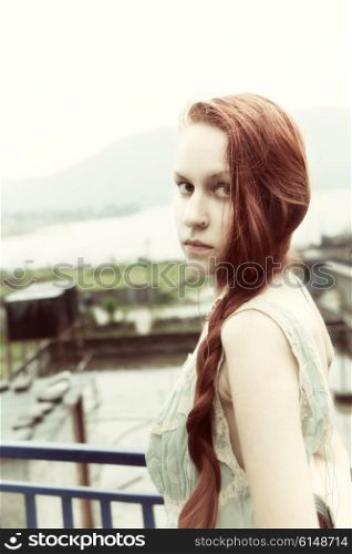 Portrait of beautiful young woman with long red hair, outdoors